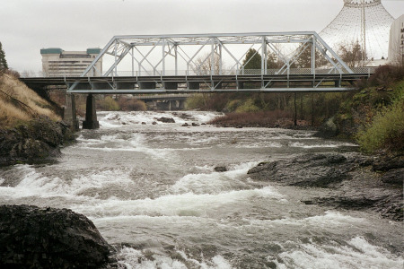 [A series of shallow, but very fast moving and frothy drops of water under a bridge not all that far above the water.]